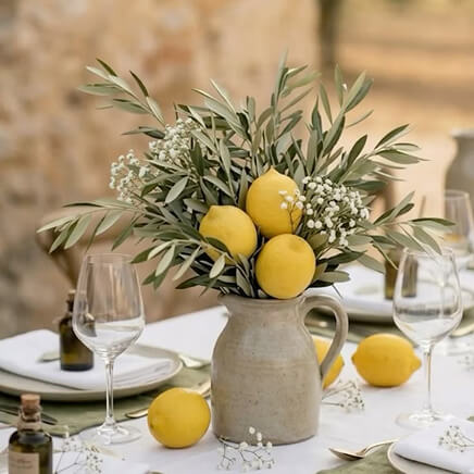 Vase en grès, branches d'olivier et citrons sur une table dressée